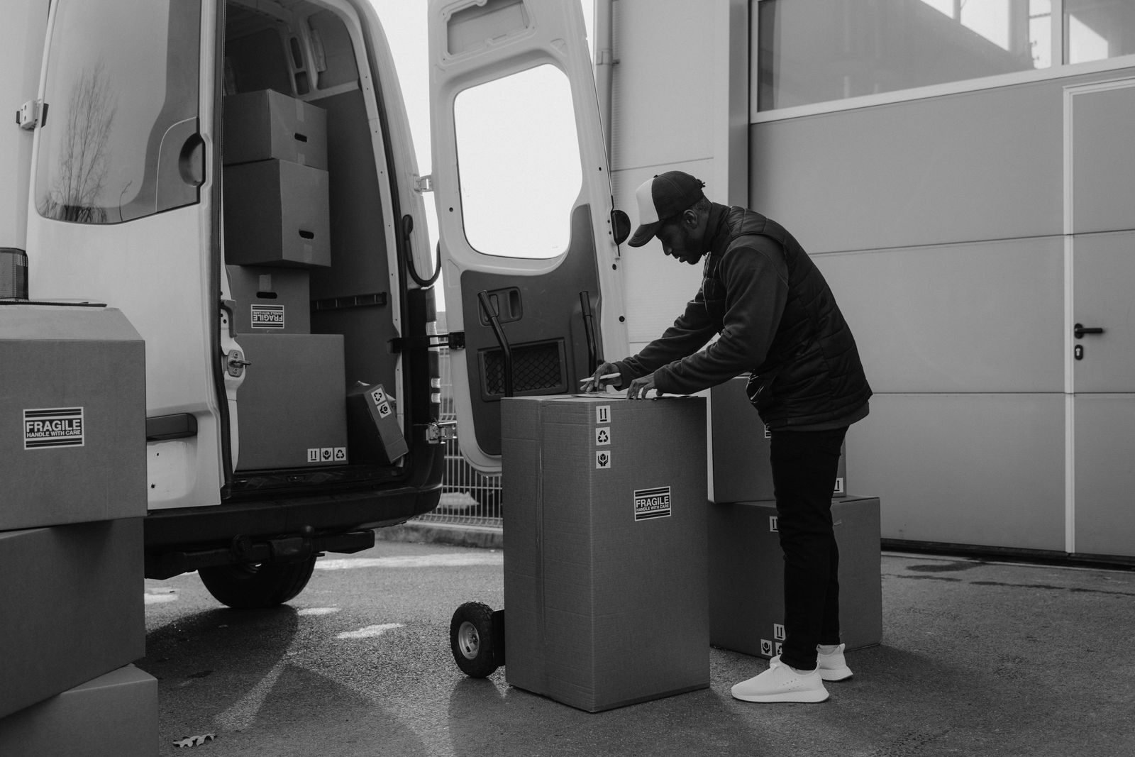 Delivery driver organizing packages near a van in an urban setting, ready for shipping.